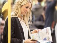 En kvinna står och läser tidningen i metrotåget